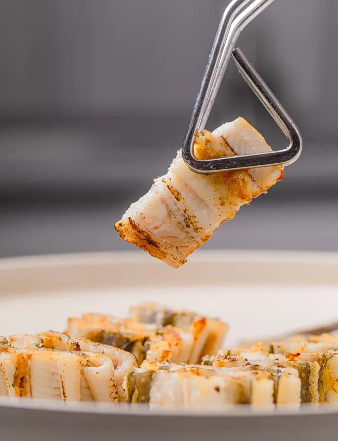 An eel roll held with tongs