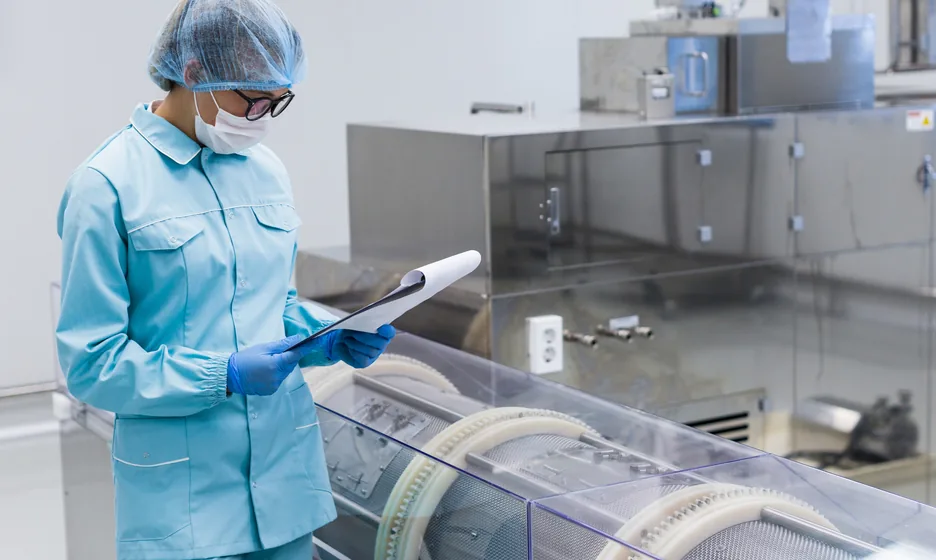 A worker in hygiene clothing inspecting production equipment